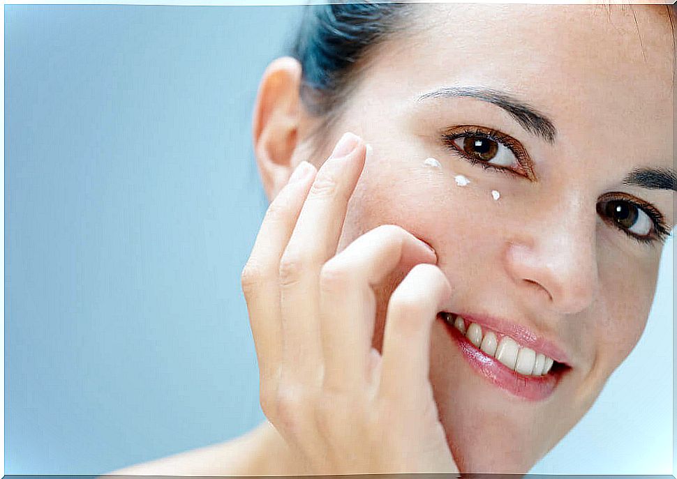 Woman putting cream under eyes to prevent dark circles 